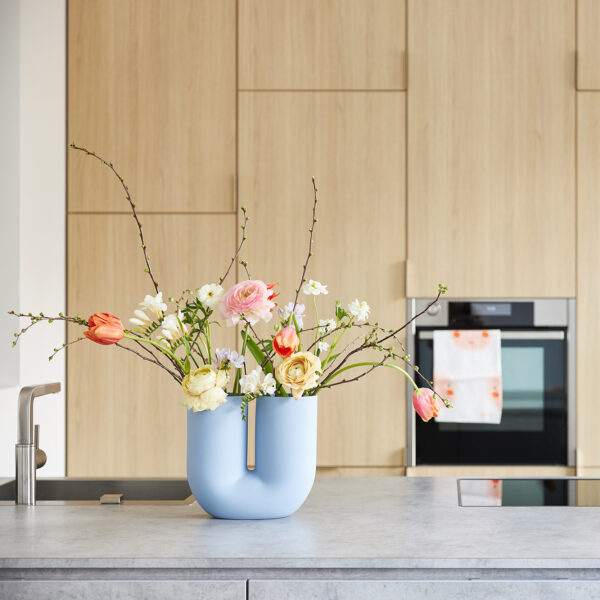 A modern spring bouquet with freesias, ranunculus and tulips in a beautiful vase in a designer kitchen